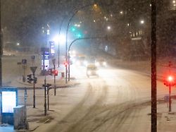 autos fahren am morgen bei schneefall eine strasse an den landungsbruecken entlang