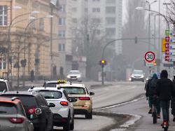 autos fahren in der potsdamer innenstadt auf der breiten strasse an radfahrern und einem rollerfahrer vorbei