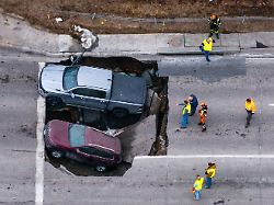 beamte begutachten einen unfall bei dem zwei fahrzeuge auf der pacific street oestlich der 67th street in omaha in ein sinkloch gestuerzt sind