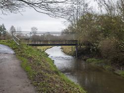borken nordrhein westfalen deutschland kleine fussgaengerbruecke ueber einen fliessenden bach mit einem gewundenen feldweg am ufer im herbst