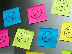 bunte post its mit traurigen gesichtern symbolisieren unzufriedenheit im job und die belastungen im arbeitsalltag