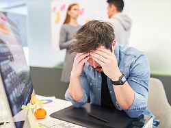 business mann als grafikdesigner am pc hat kopfschmerzen wegen ueberlastung