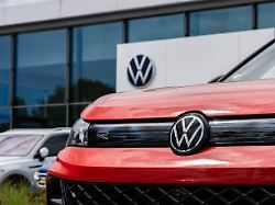 das logo des deutschen automobilherstellers volkswagen ist vor einem vw autohaus auf einem fahrzeug zu sehen