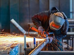 deutschland themenfoto metallindustrie ein industriearbeiter flext mit einem winkelschleifer ein stahlrohr