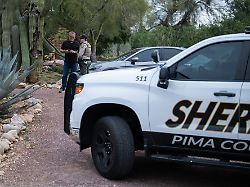 ein beamter des pima county sheriffs unterhaelt sich mit einem privaten sicherheitsbeamten vor dem haus von nancy guthrie