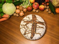 ein laib brot mit einem kreuz und obst und gemuese im hintergrund themenfoto vom 24 01 2026
