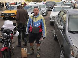 ein mann der eine jacke in den farben der venezolanischen flagge traegt steht an einer tankstelle an um benzin zu kaufen