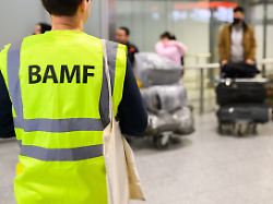 ein mitarbeiter vom bamf bundesamt fuer migration und fluechtlinge steht im flughafen hannover vor afghaninnen und afghanen aus den bundesaufnahmeprogrammen