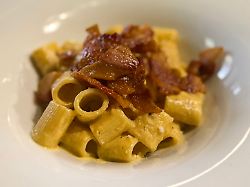 ein teller mit pasta carbonara einem typischen italienischen nudelgericht steht auf einem reatuaranttisch
