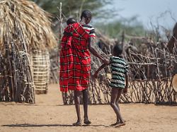 ein vater hilft seinem unterernaehrten sohn beim gehen in der naehe ihrer huette in dem dorf lomoputh im norden kenias