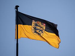 eine flagge des landes baden wuerttemberg weht vor blauem himmel im wind