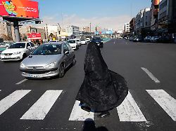 eine frau ueberquert eine kreuzung in der innenstadt von teheran