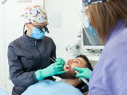 eine zahnaerztin untersucht einen maennlichen patienten in einer zahnarztpraxis mit professionellem werkzeug und persoenlicher schutzausruestung