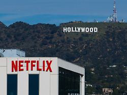 file a netflix sign is displayed atop a building in los angeles on dec 18 2025 with the hollywood sign in the distance ap photo jae c