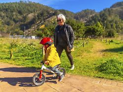 grossmutter die ihrem enkel in einem sonnigen park das fahren auf einem balance bike beibringt um das miteinander der generationen und aktivitaeten im freien zu foerdern modellfreigabe vorhanden
