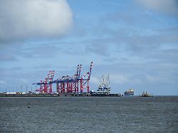 industriehafen mit markanten roten kranen unter teilweise bewoelktem himmel jadeweserport wilhelmshaven friesland niedersachsen deutschland