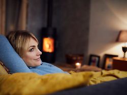 mid adult woman relaxing at home in front of a fireplace model released symbolfoto property released rbf09955