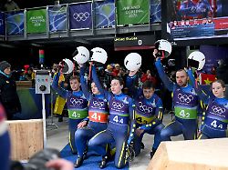 olympia olympische winterspiele mailand cortina 2026 rodeln staffel mixed im cortina sliding centre das team der ukraine kniet am boden und hebt im zielbereich gemeinsam die helme nach oben