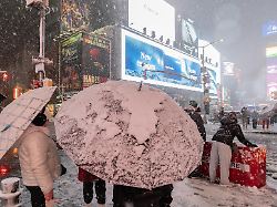 passanten sind bei starkem schneefall auf dem times square in new york unterwegs