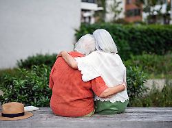 rear view of elderly mother hugging mature daughter rear view of elderly mother hugging mature daughter sitting on bench