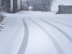 reifenspuren von winterreifen im frischen schnee auf einer vereisten strasse verdeutlichen glatte fahrbahnverhaeltnisse und erhoehte rutschgefahr bei winterlichem wetter