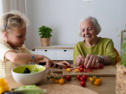 smiling grandmother and granddaughter cutting vegetables on table model released symbolfoto property released svkf01497