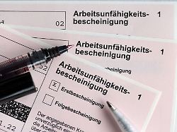 stifte liegen auf arbeitsunfaehigkeitsbescheinigungen