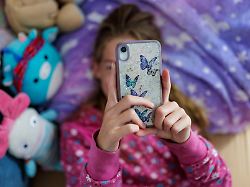 symbolfoto zum thema handynutzung bei kindern ein maedchen liegt in ihrem bett und ist am handy berlin 22 07 2025