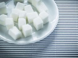 untertasse mit zuckerwuerfeln auf gestreiftem hintergrund