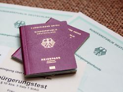 zwei deutsche reisepaesse liegen auf einbuergerungsurkunden der bundesrepublik deutschland sowie einem einbuergerungstest