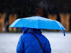 2026 01 04 13 51 40 amsterdam eine frau mit regenschirm geht durch einen winterschauer hagel und schneeschauer ziehen ueber die niederlande