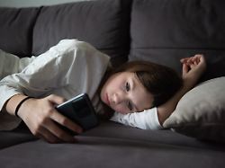 a sad teenage girl is lying with a smartphone in the dark sadness problems the concept of myopia