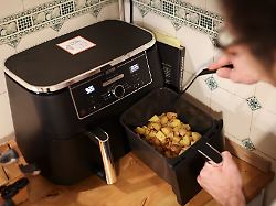 archiv 09 02 2026 hamburg ein mann kocht in seiner kuechen mit einer heissluftfritteuse airfryer ein gericht aus kartoffelstuecken und gebratenem huehnerfleisch