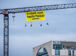 aktivisten der umweltschutzorganisation greenpeace haengen mit einem transparent freiheit statt fossile politik an einem kran auf dem gelaende des bundeskanzleramtes
