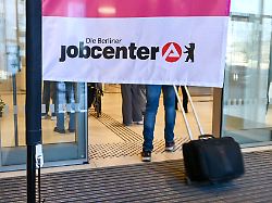 besucher gehen in den eingang zum jobcenter friedrichshain kreuzberg ueber dem ein banner mit der aufschrift die berliner jobcenter haengt