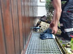 ein lieferant bringt heizoel zu einem haus das oel wird ueber einen zapfhahn direkt in den heizoeltank im keller gepumpt schutzkleidung