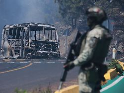 ein soldat steht in mexiko einem der drei ausrichterlaender der fussball wm im sommer neben einem ausgebrannten bus