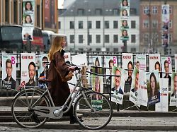 eine frau geht an wahlkampfplakaten im vorfeld der parlamentswahlen vorbei