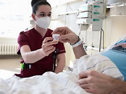 eine pflegerin gibt in einem krankenzimmer im klinikum stuttgart einem patienten tabletten