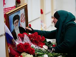 eine tadschikische frau weint waehrend sie ein portraet des getoeteten iranischen obersten fuehrer chamenei vor der iranischen botschaft beruehrt