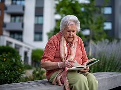elderly woman reading a book outdoors in urban garden elderly woman reading a book outdoors in urban garden quiet afternoon moment