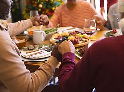 hands of diverse group of senior friends saying grace at christmas dinner in sunny dining room retirement friendship christmas celebration meal senior lifestyle communication unaltered