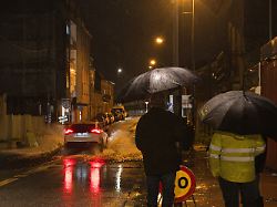 menschen stehen im regen auf einer ueberfluteten strasse in o santo das sturmtief leonardo hat suedspanien mit starkregen und orkanboeen fuer ueberschwemmungen erdrutsche und erhebliche schaeden gesorgt