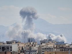 people watch from a rooftop as a plume of smoke rises after a strike in tehran iran sunday march 1 2026 1