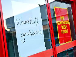 schilder mit aufschrift dauerhaft geschlossen und wir schliessen diese filiale symbolfoto konkurs insolvenz