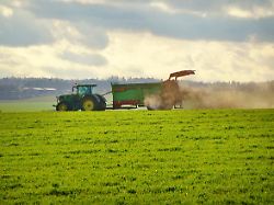 stoffkreislauf organische duengung erhaltung der bodenfruchtbarkeit traktor mit miststreuer fuer festmist auf einem feld bei der arbeit landwirtschaft im november