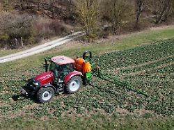 themenfoto landwirtschaft duengen pestizide ein landwirt faehrt mit seinenm traktor ueber ein gruenes feld und duengt mit pestiziden