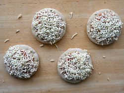 tiefgekuehlte mini pizza margherita auf einem kuechenbrett