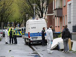 vor dem mehrfamilienhaus der familie stehen beamte der polizei auf dem gehweg und der strasse