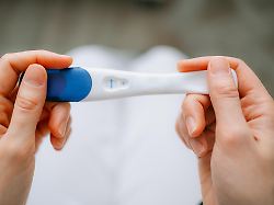 woman holding a non positive pregnancy test result experiencing emotions related to family planning fertility and the journey of trying to conceive or avoiding pregnancy modellfreigabe vorhanden
